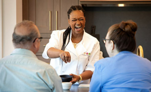 Personal chef laughing with clients in their home kitchen.