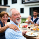 Older couple smiles while eating a healthy meal outdoors with family