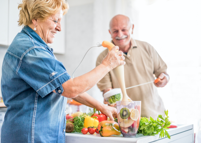 Older couple prepares fresh fruits and vegetables in kitchen